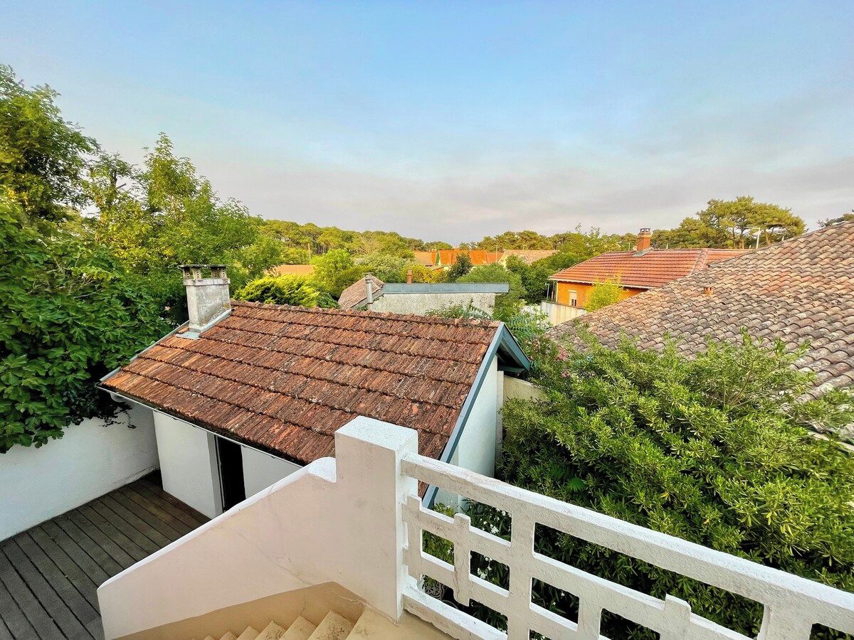 Zona residencial con casas escalonadas, cerca blanca y abundante vegetación.