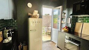 Eine moderne Küche mit einem weißen Kühlschrank, einer Holzausziehtafel und einem schwarzen Herd.
