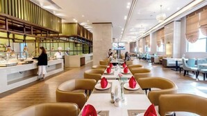A modern restaurant with a long counter, round tables, and a bar area. - Ronghu Hotel (Yueyang County)