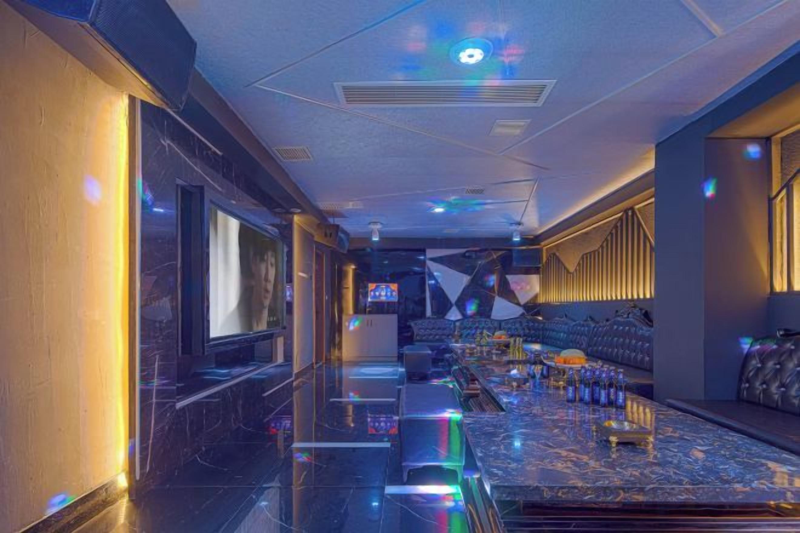 A bar area with a long counter, seating, and a television screen.