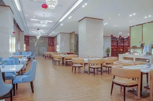 Un restaurante espacioso con varias mesas y sillas, suelo de madera y una decoración de estilo moderno.