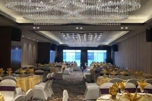Un salón de banquetes con filas de mesas, sillas y una gran lámpara de araña.