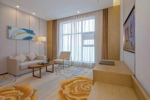 Habitación de hotel con sofá, sillón, mesita de centro y escritorio.