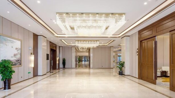 A spacious, well-lit hallway with a large chandelier, potted plants, and wooden doors. - Ronghu Hotel (Yueyang County)