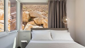 Une chambre à coucher avec un lit, une fenêtre et une vue sur des rochers.
