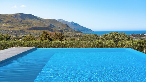 Une piscine avec vue sur les montagnes et la mer.