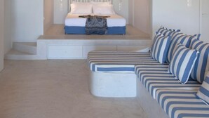 Une chambre à coucher comprenant un lit, des tables de chevet, un canapé et une tête de lit.