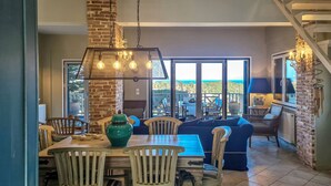 Un coin repas avec une cheminée en briques, des chaises en bois et une table. Une grande fenêtre offre une vue sur l’extérieur.
