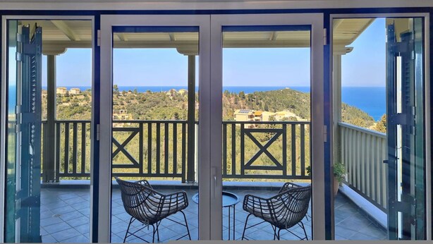 Un balcon avec deux chaises, une vue sur la mer et un bâtiment en arrière-plan.