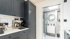 Una cocina moderna con armarios oscuros, una cafetera y una encimera blanca.