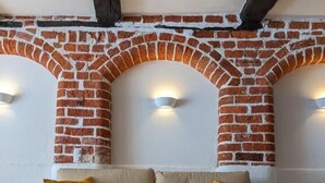 Ein Wohnzimmer mit Kamin aus Backsteinen, einer gelben Kissen ausgelegten Couch und einem Holztisch.
