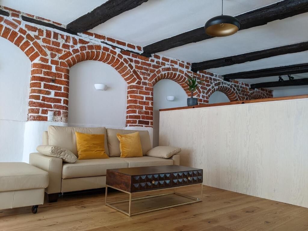En stue med murstensvæg, sofa, sofabord og hængende lampe.