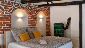 Ein Schlafzimmer mit Backsteinwand, einem Bett mit gemusterten Betttextilien und zwei Wandleuchten.
