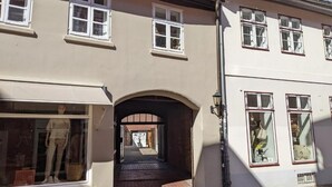 Ein Gebäude mit vielen Fenstern, einem Rundbogenportal und einer Schaufensterpuppe.