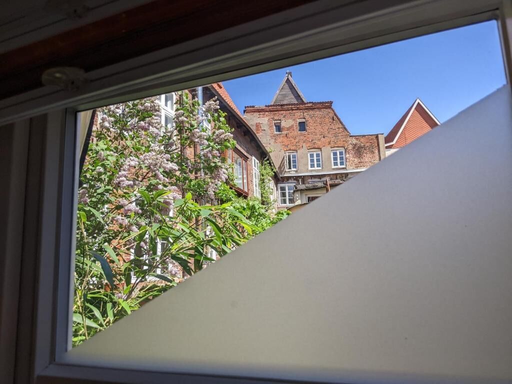 Vista desde una ventana de un edificio con fachada de ladrillo y varias ventanas.