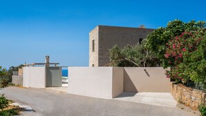 A modern house with a stone facade, a clear view of the sea, and a gated entrance. - New Villa with spectacular 180° Sea View,Private Pool & BBQ,5 min from the Beach (Rethymnon)