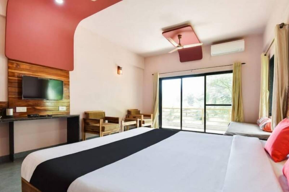 Ein Hotelzimmer mit einem großen Bett, einem Schreibtisch mit Flachbildfernseher, einer Sitzecke mit Sesseln und einem großen Fenster mit Blick.