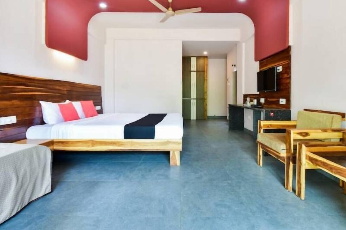 Ein Hotelzimmer mit Bett, Schreibtisch, Stuhl, Fernseher und Deckenventilator.