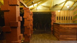 A rustic interior with a brick wall, wooden ceiling beams, and a wooden counter. - Laguna Beach Resort Murud (Dapoli)