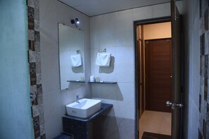 Une salle de bain moderne avec un lavabo blanc, un miroir et une porte en bois.
