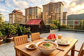 Une table à manger, dressée avec des plats et des boissons, sur une terrasse en toit, avec des bâtiments en arrière-plan.