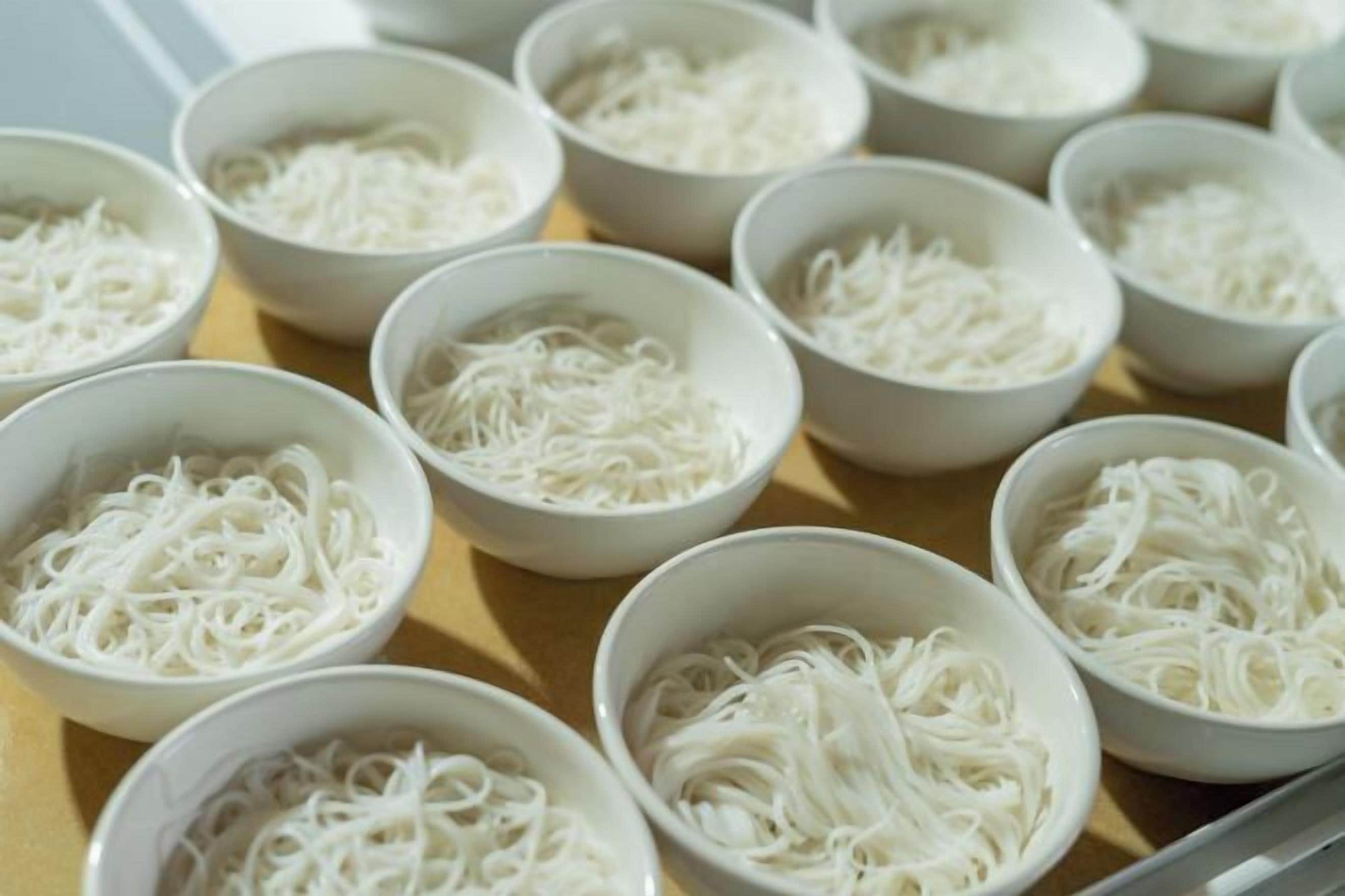 Vários recipientes com macarrão branco dispostos sobre uma mesa.