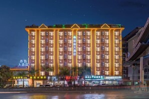 Un hôtel à plusieurs étages, doté d’une enseigne lumineuse et d’un bassin d’eau réfléchissant situé devant l’entrée.