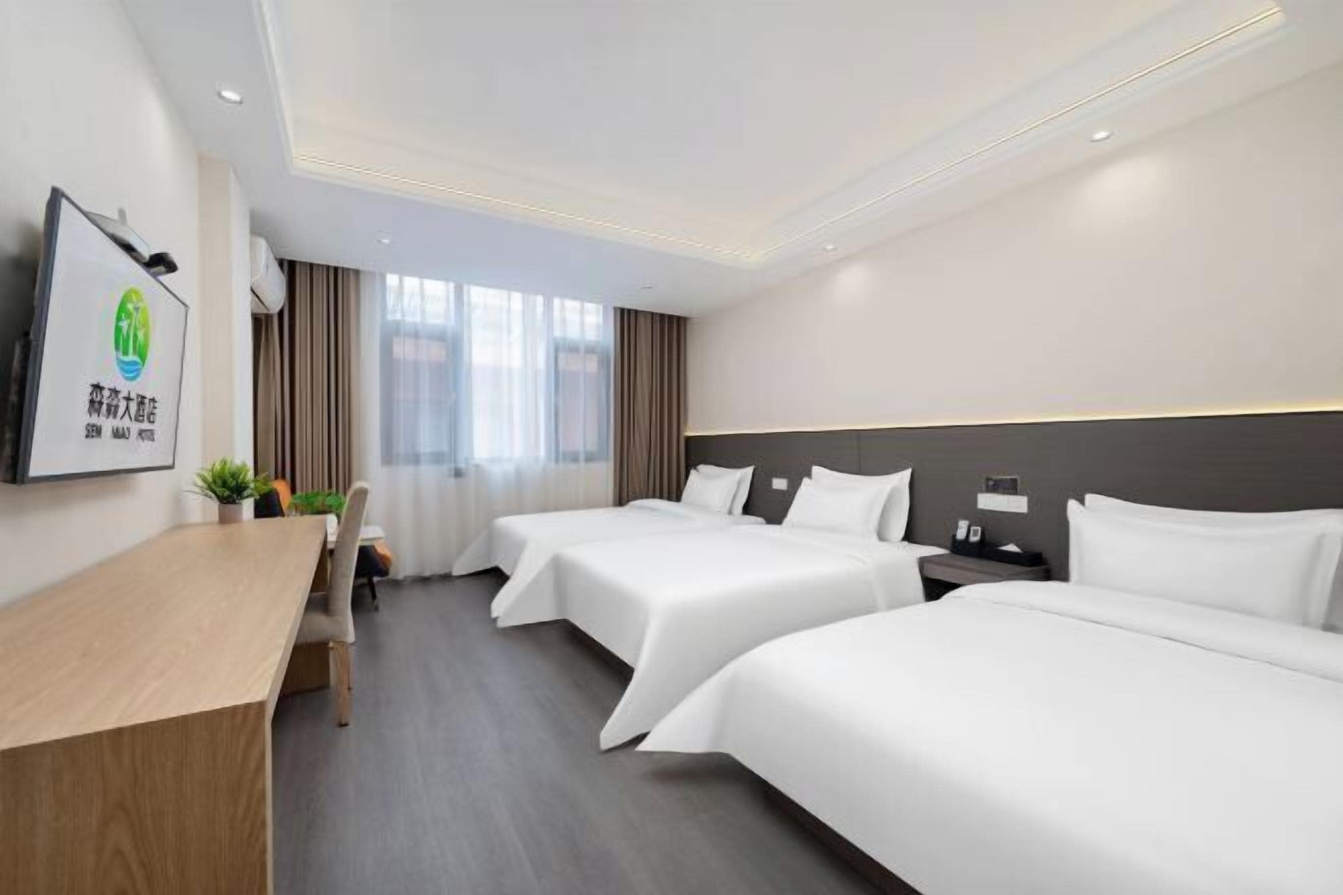 A hotel room with two beds, a desk, a chair, and a TV on the wall.
