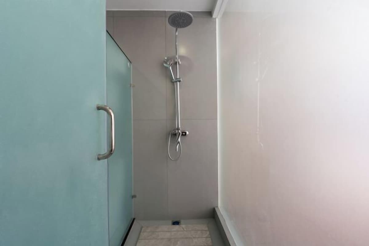 Un petit espace douche fermé, équipé d’un pommeau de douche à main et d’un robinet à main.