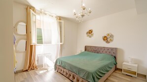 A bedroom with a bed, a nightstand, a mirror, and a chandelier.