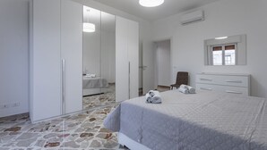 Une chambre à coucher avec un lit, une armoire, un miroir et une fenêtre.
