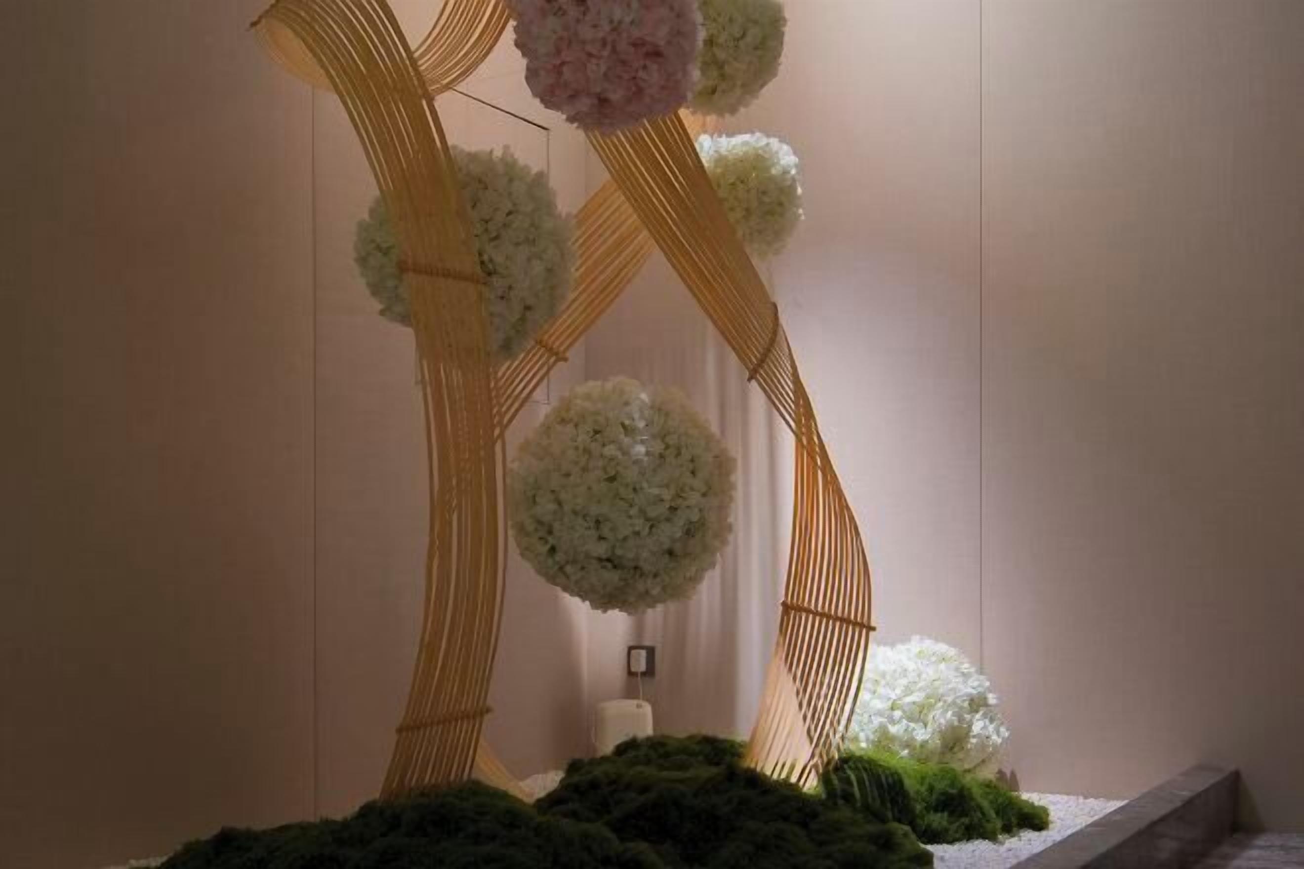 En korridor med en struktur av bambu och vita blomsterarrangemang.