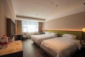 Quarto de hotel com duas camas, uma escrivaninha, uma cadeira e uma janela grande com cortinas.