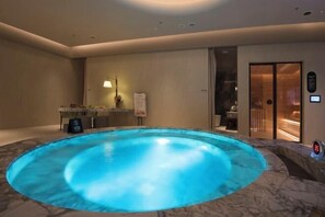 Uma área de spa com piscina aquecida, balcão de recepção e sala de sauna.