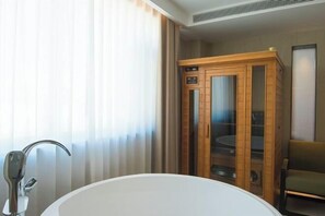 Um banheiro moderno com uma banheira independente, um armário de madeira com portas de vidro e uma cadeira.