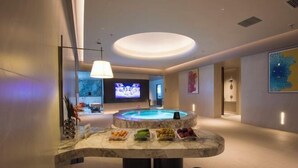 A modern spa area with a hot tub, a marble reception desk, and a television screen. - Jinlongtan jiudian (Zhaodong)
