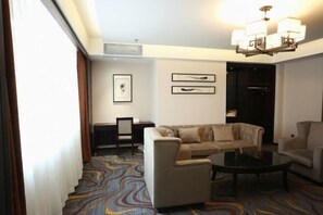 A hotel room with a sofa, armchairs, a coffee table, and a desk. - Jinlongtan jiudian (Zhaodong)