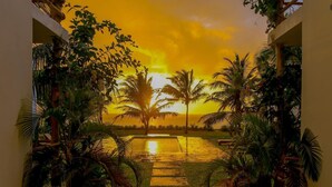 A pathway leading to a sunset view with palm trees and a building entrance. - Ahadi Beach Villa, beautifully modern with pool beach access fantastic sea views (Mtwapa)