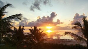 A sunset over a beach with palm trees. - Ahadi Beach Villa, beautifully modern with pool beach access fantastic sea views (Mtwapa)