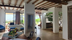 A spacious living area with a high ceiling, a dining table with chairs, and a view of the outdoors. - Ahadi Beach Villa, beautifully modern with pool beach access fantastic sea views (Mtwapa)