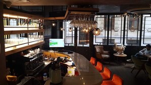 Zona de bar amb un taulell corbat, diversos vasos de vi penjant a sobre i un monitor informàtic a la paret.