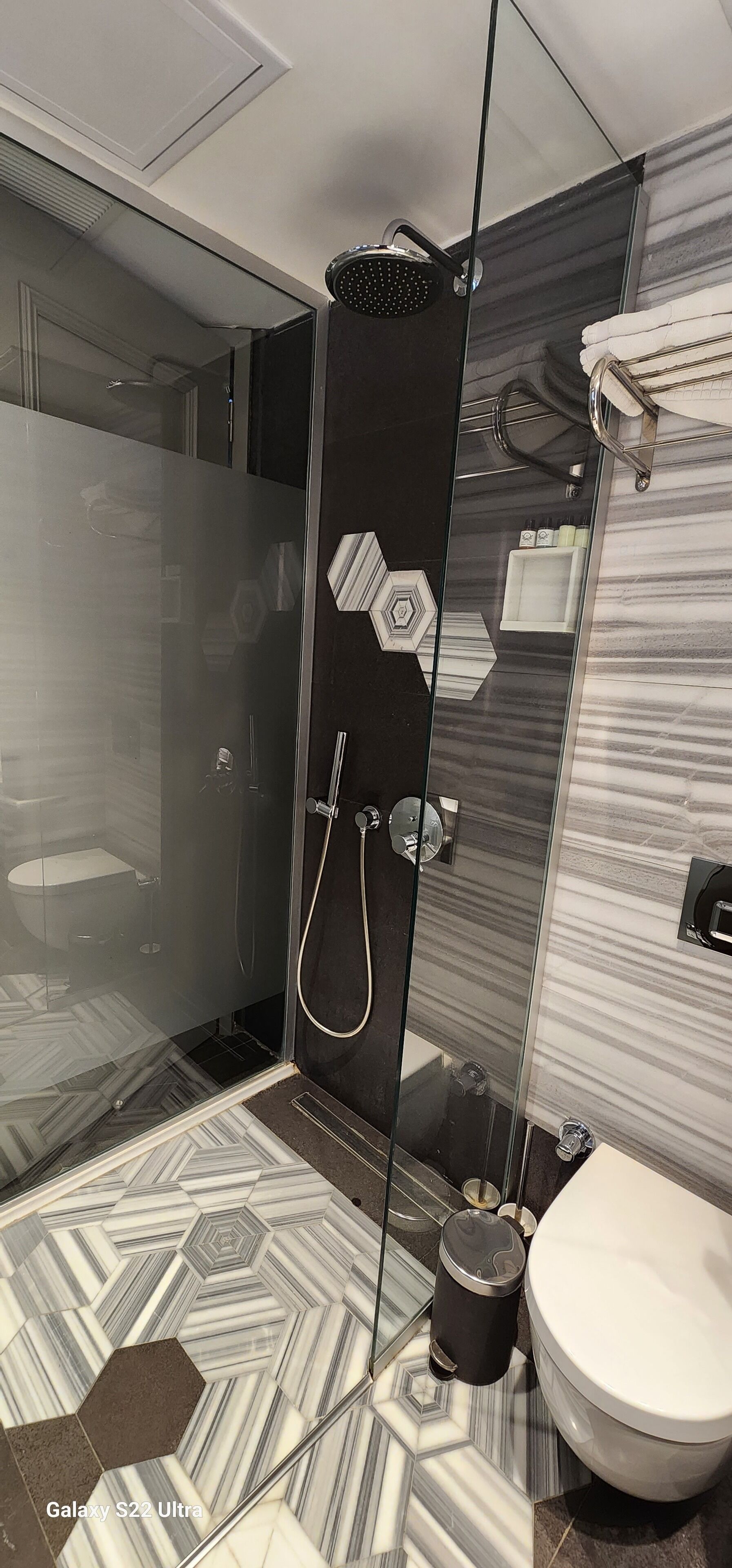 A modern bathroom with a glass-enclosed shower, a toilet, and a sink.