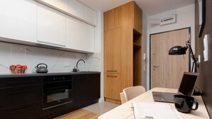 A modern kitchen with black cabinetry, a wooden cabinet, a laptop, a black mug, and a book on a table.