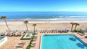 Área de piscina à beira-mar com espreguiçadeiras e piscina, com vista para o oceano.