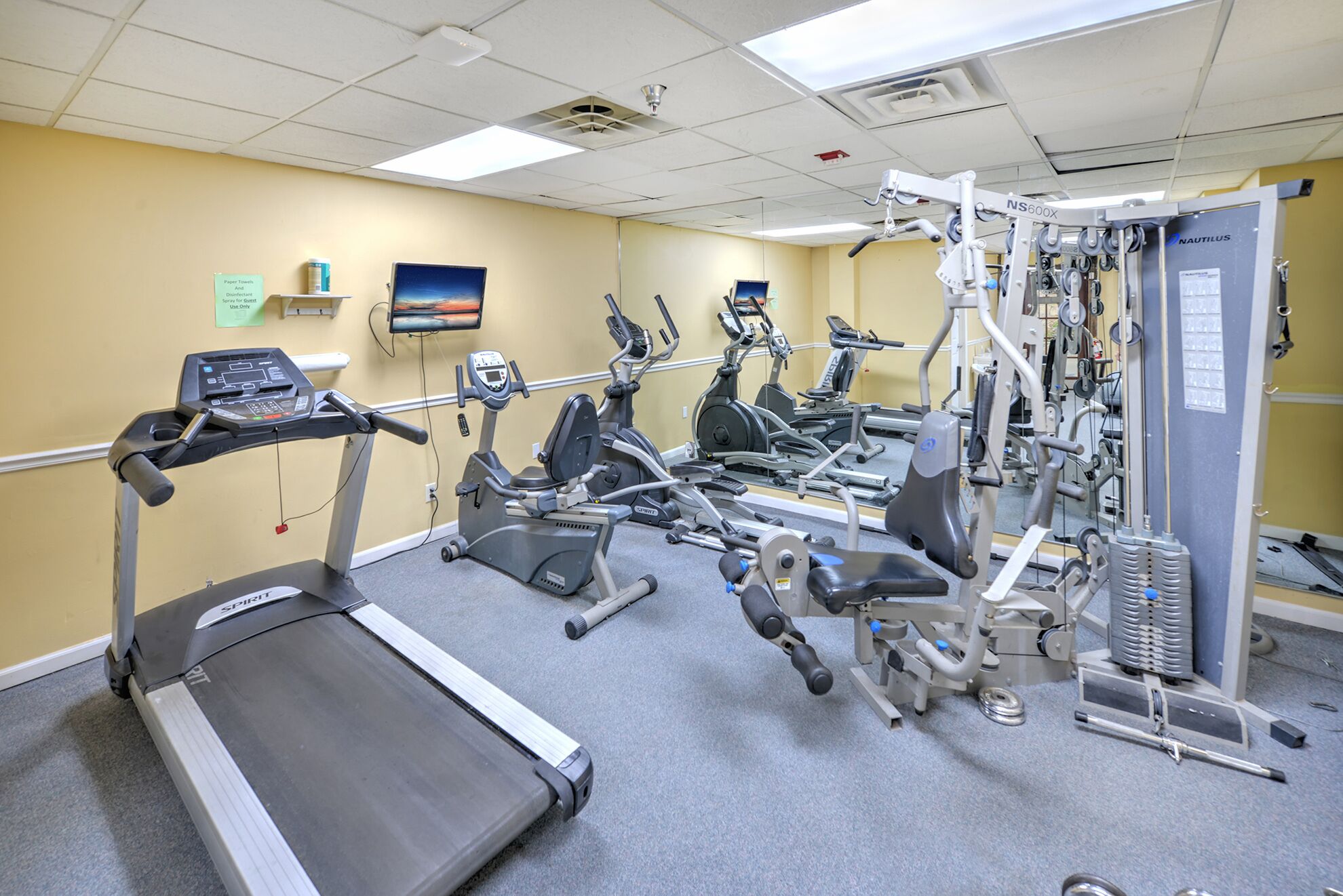 Un gimnasio con cintas de correr, elípticas y equipo de pesas.