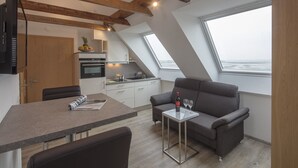 Eine moderne Küche mit Einbauofen, ein Essbereich mit Tisch und Stühlen sowie ein Sofa mit Meerblick.