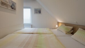 Ein Schlafzimmer mit zwei Betten, einem Kopfteil und einem Fenster mit Jalousien.