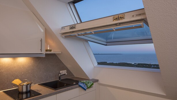 Eine Küche mit Einbauherd, Spüle und Fenster mit Meerblick.
