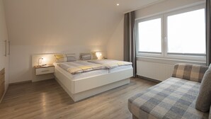 Un dormitorio moderno con una cama grande, mesitas de noche, una ventana con cortinas y vistas al exterior.