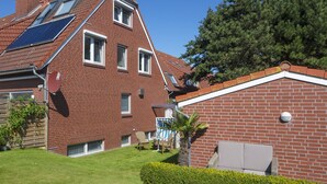 A two-story brick house with a sloped roof, solar panels, and a small attached garage. - APARTMENT 2 ON THE 2ND FLOOR (Norderney)